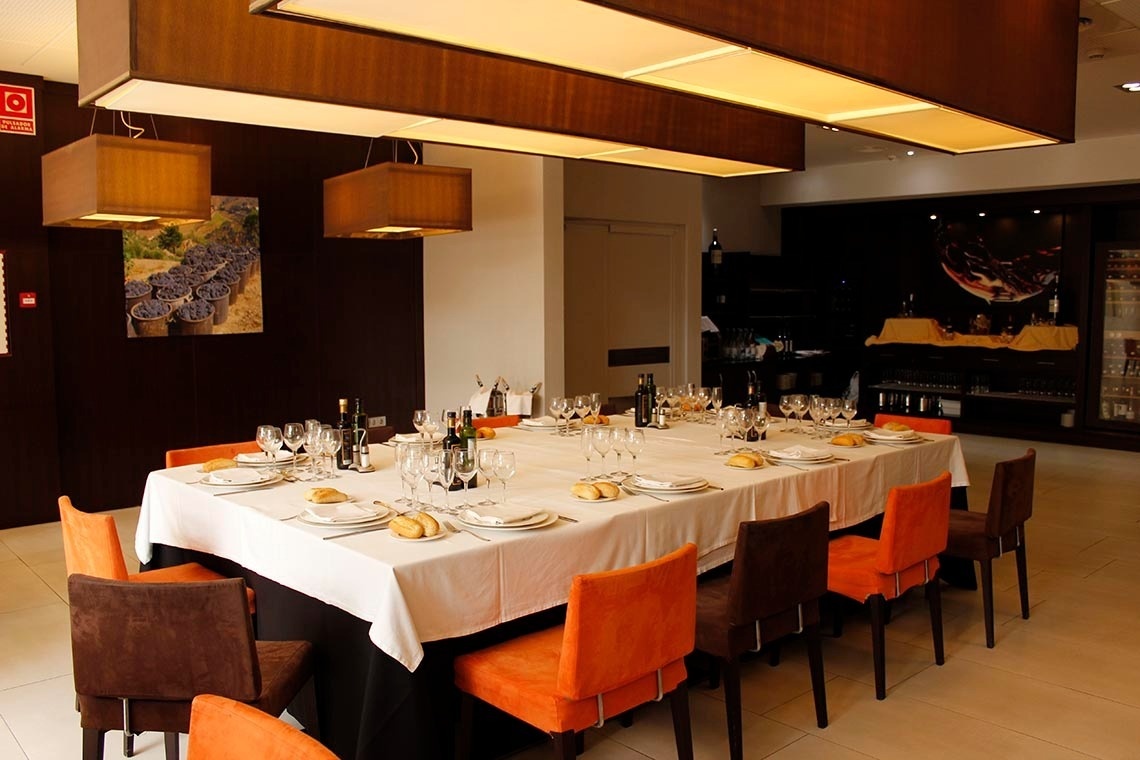 una habitación con una mesa larga y sillas naranjas