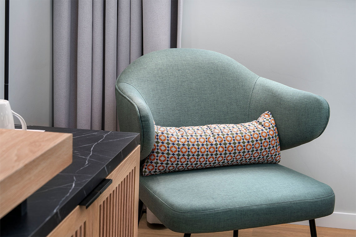 Sillón turquesa con cojín estampado y mesa auxiliar de mármol en hotel ZT: Villa Olimpica.