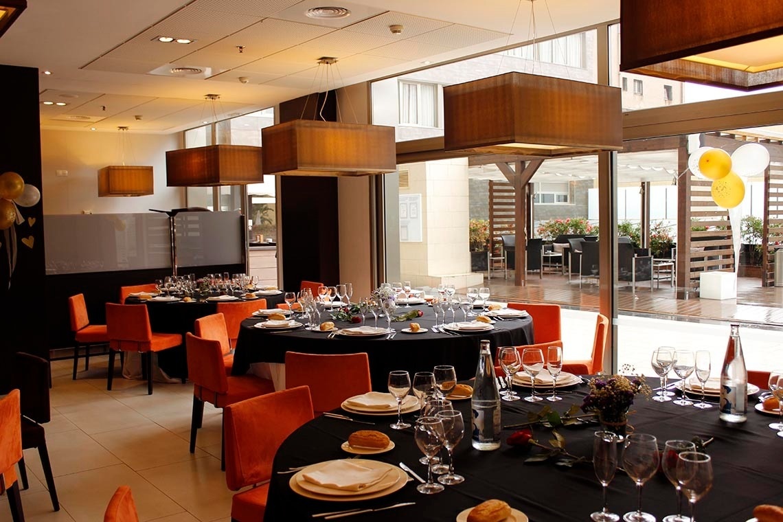 una habitación llena de mesas y sillas con platos y copas de vino