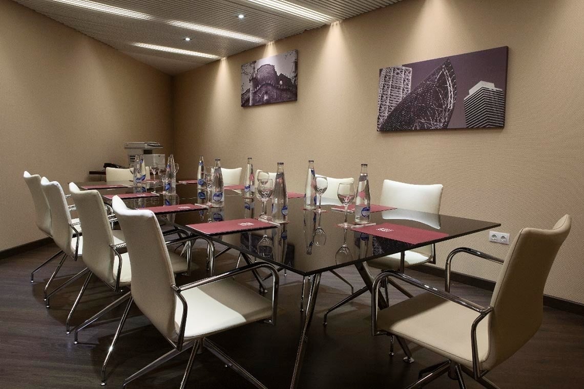 una sala de conferencias con mesas y sillas y botellas de agua