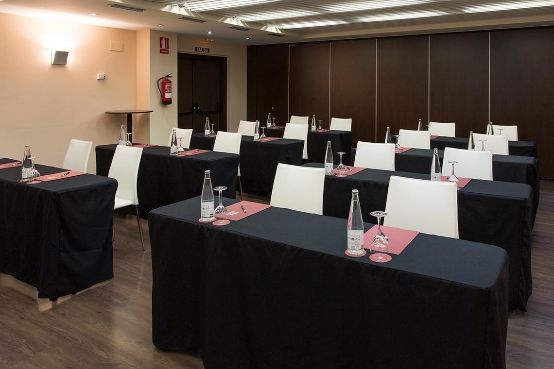 una sala de conferencias con mesas y sillas y un extintor en la pared