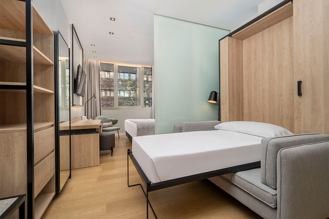 Habitación de hotel moderna con cama desplegable y sala de estar. ZT: Villa Olimpica