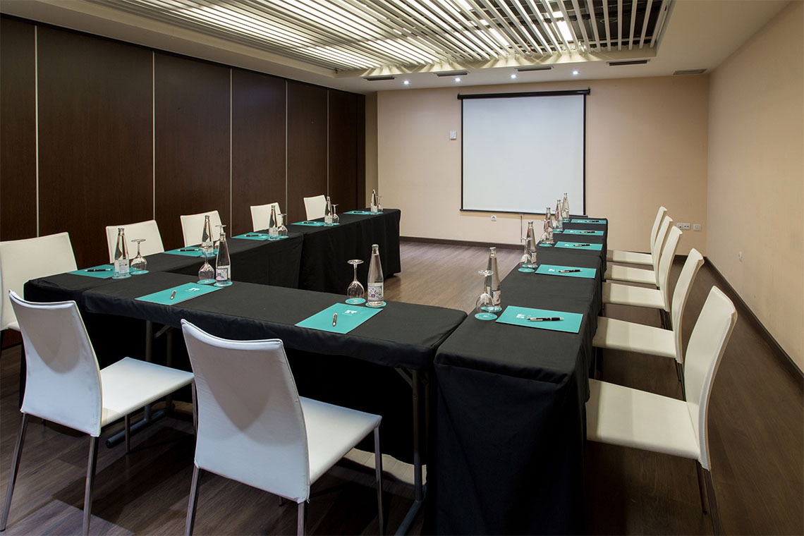 Modern meeting room with black glass table, white chairs and abstract art. Perfect for ZT: Villa Olimpica events.