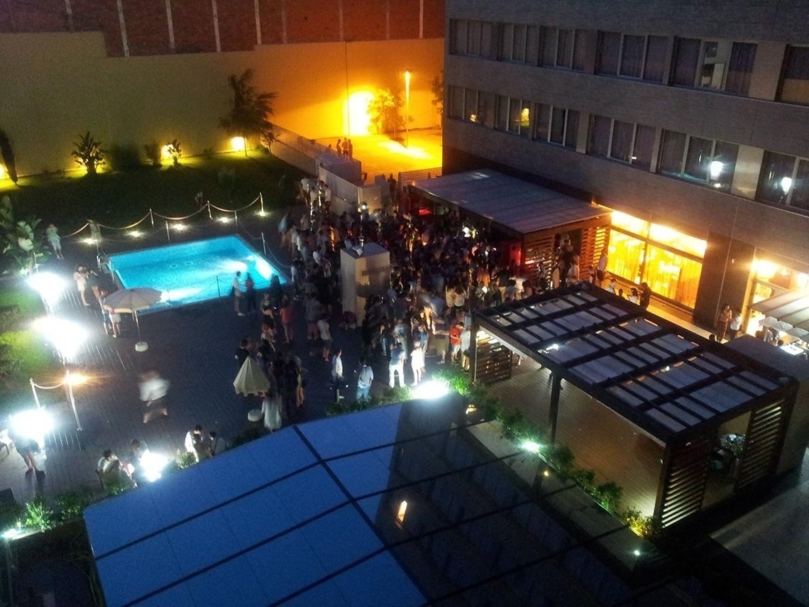 una gran multitud se reúne alrededor de una piscina en la noche