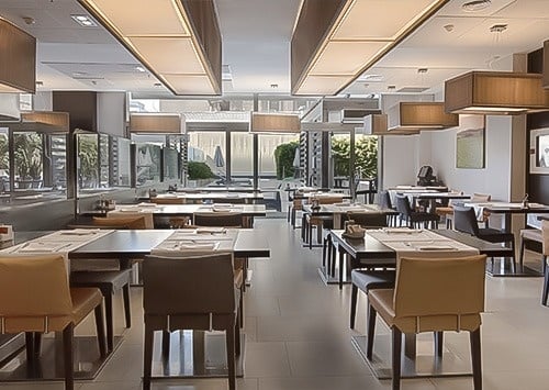 un chef prepara comida en un restaurante con mesas y sillas