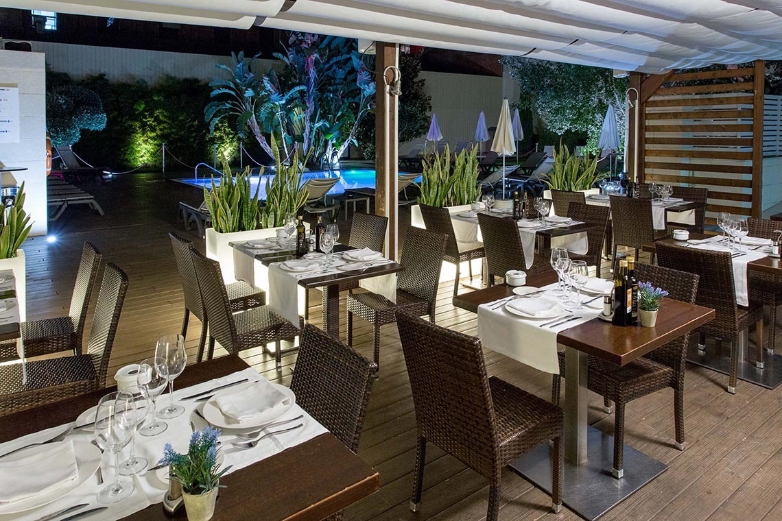 un restaurante con mesas y sillas y una piscina en el fondo