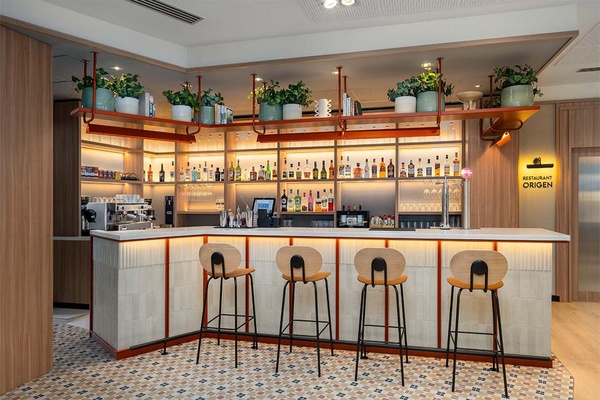 Bar moderno en Hotel Villa Olimpica con taburetes y licores.