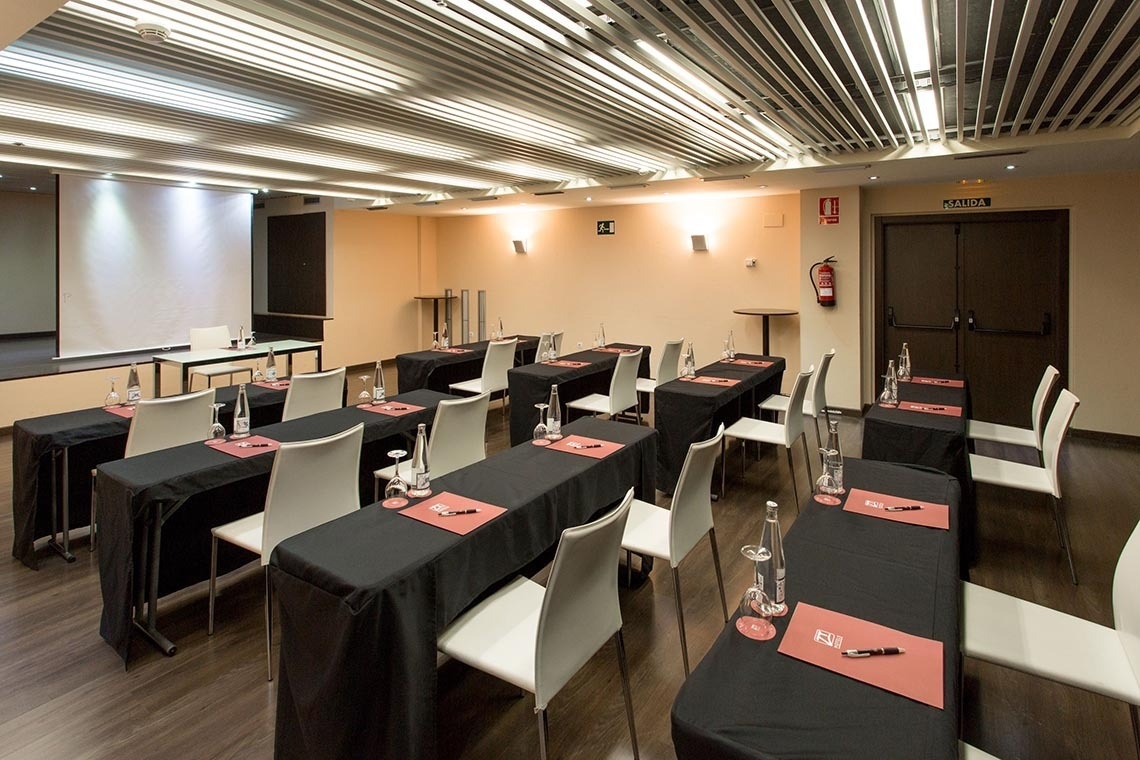 una sala de conferencias con mesas y sillas y una puerta de salida