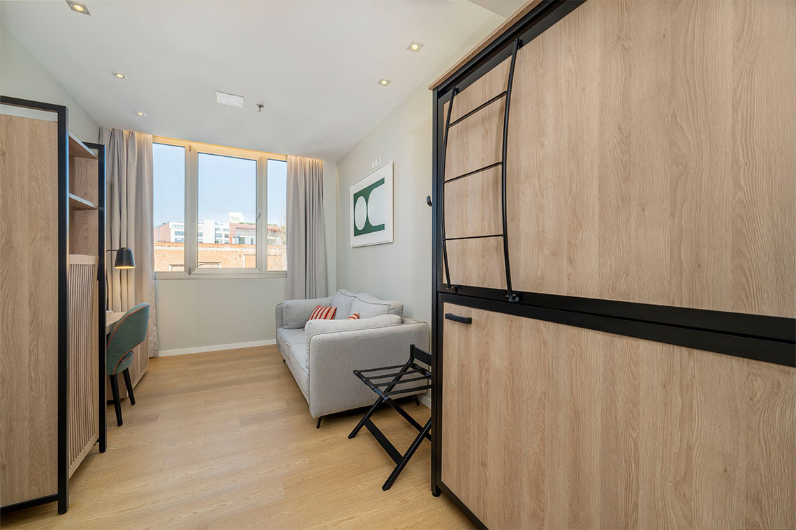 Amplia habitación de hotel con sofá, escritorio y armario empotrado. Espacio moderno para tuZT: Villa Olimpica.