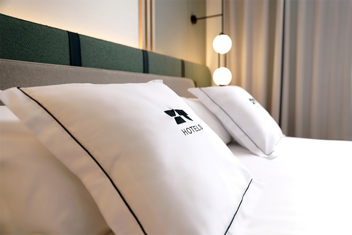 dos almohadas blancas con el logotipo de hoteles bordado en ellas