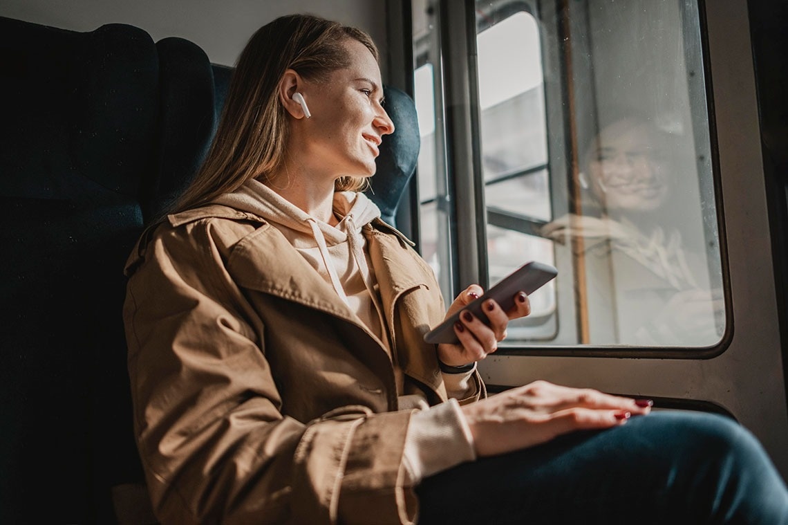 una mujer está sentada en un tren mirando su teléfono