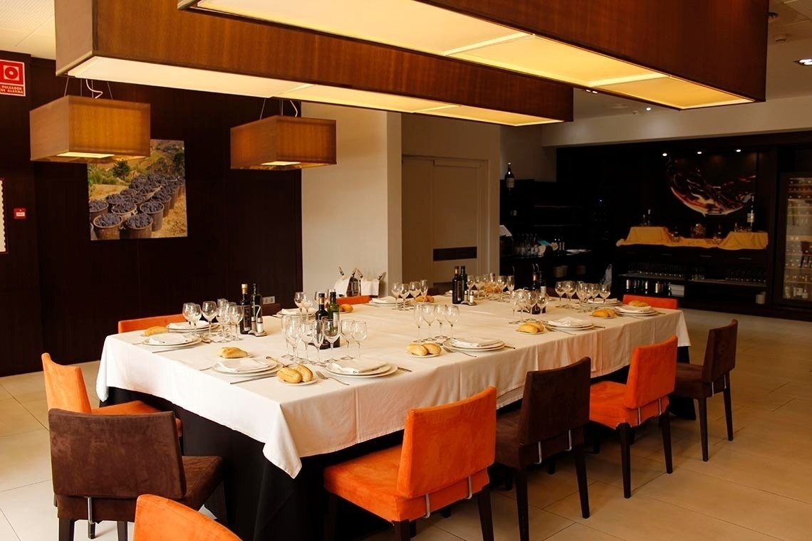 una habitación con una mesa larga y sillas naranjas