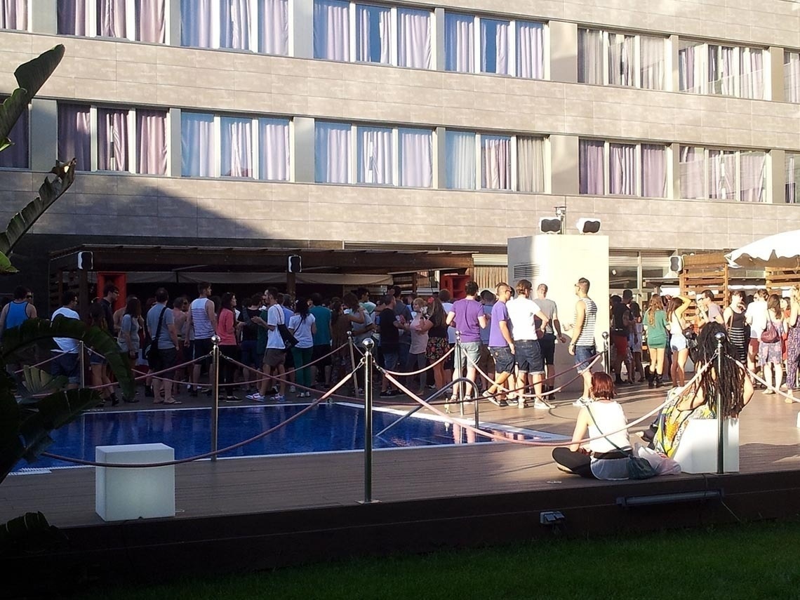 una multitud de personas se reúnen alrededor de una piscina