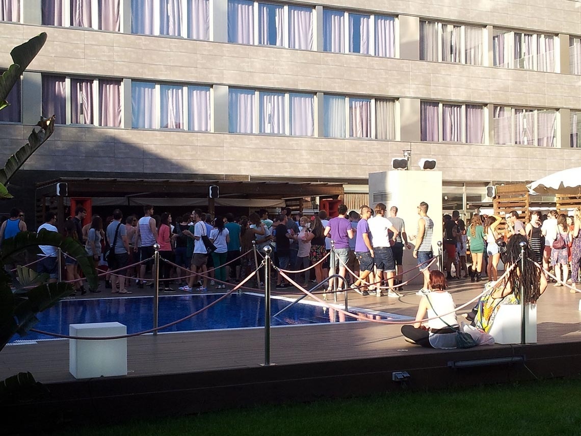 una multitud de personas se reúnen alrededor de una piscina