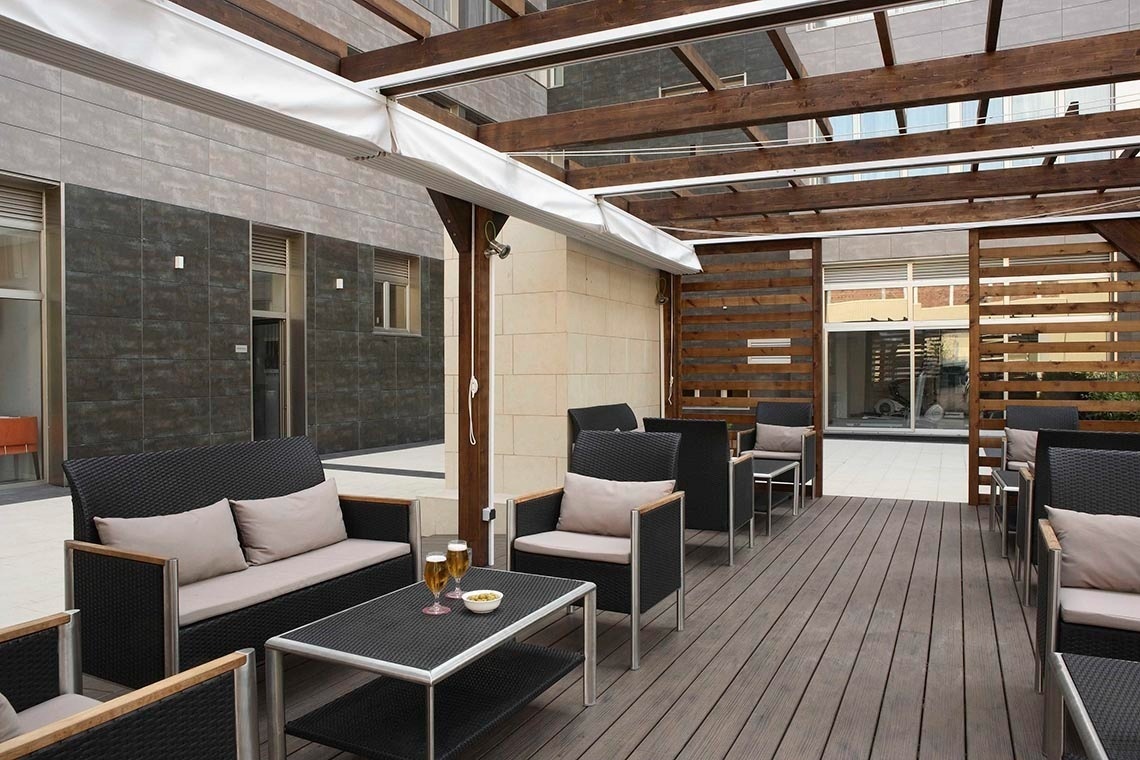 un patio con muebles y una mesa con una copa de vino