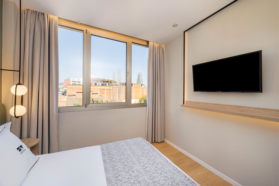 Habitación moderna con cama cómoda, TV de pantalla plana y ventana con vistas urbanas. ZT: Villa Olimpica