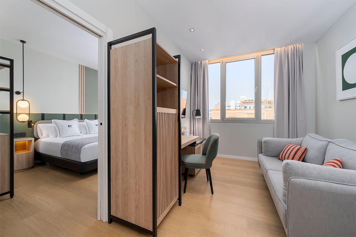 Habitación de hotel con cama y sofá. Diseño moderno y acogedor con ZT: Villa Olimpica.